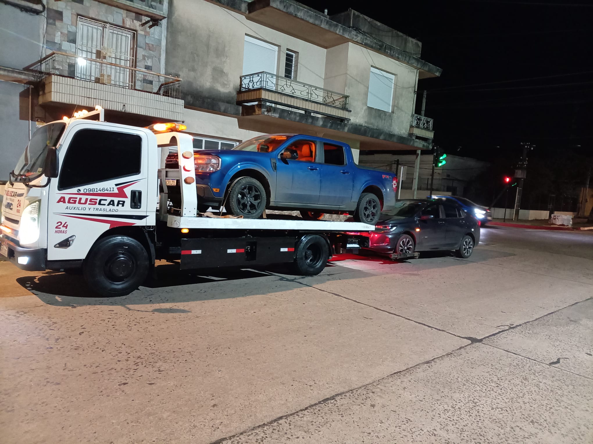 Camión de AGUSCAR trasladando una camioneta durante un servicio nocturno